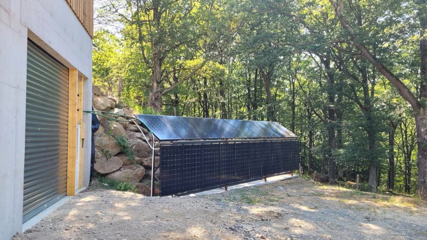 Capteurs solaires à air alignés au sol devant un hangar agricole